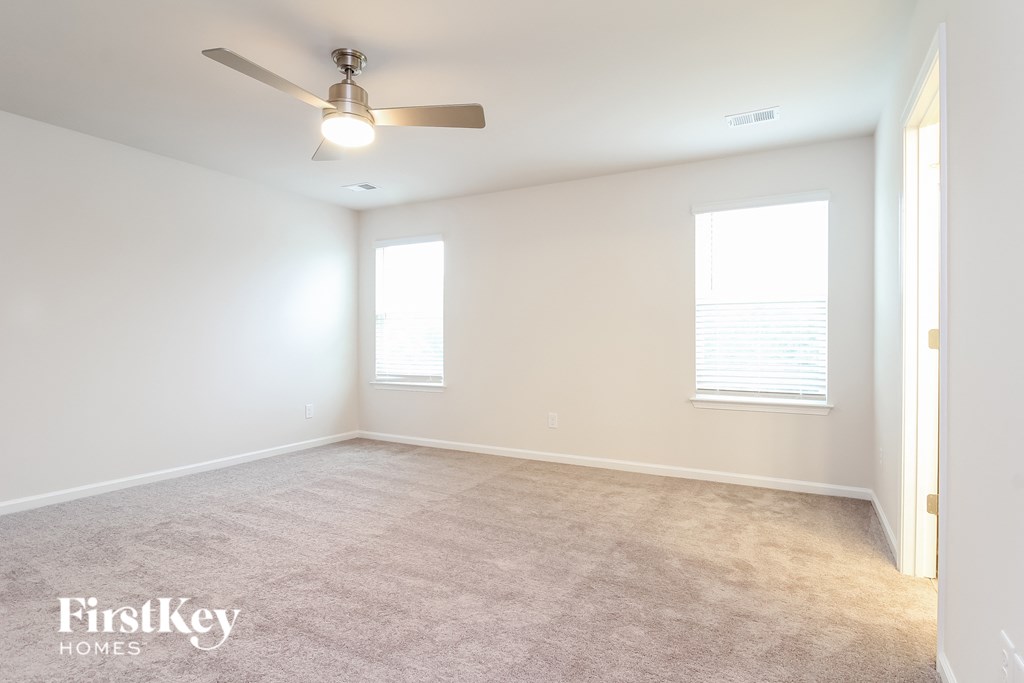 an empty living room with a ceiling fan and a window