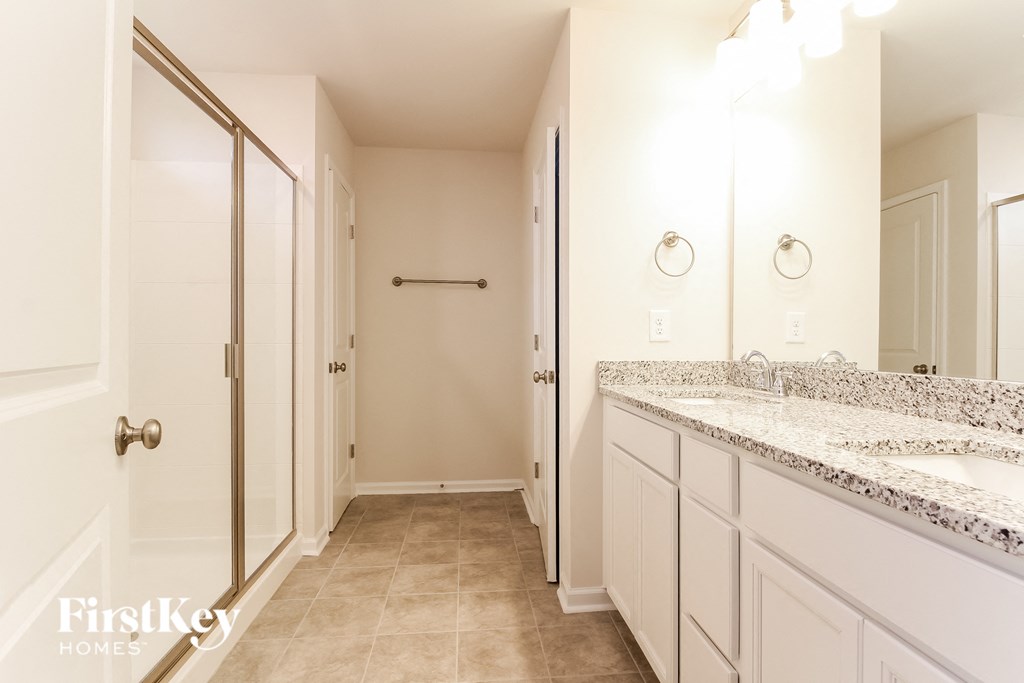 a bathroom with white cabinets and a sink and a shower
