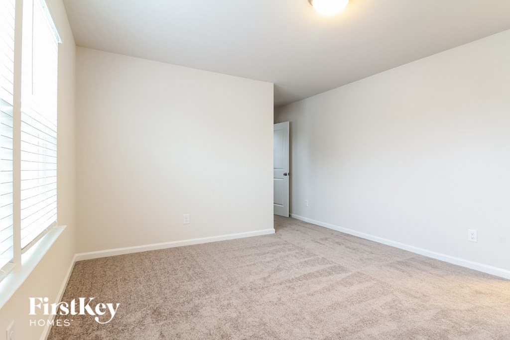 a spacious living room with white walls and carpet