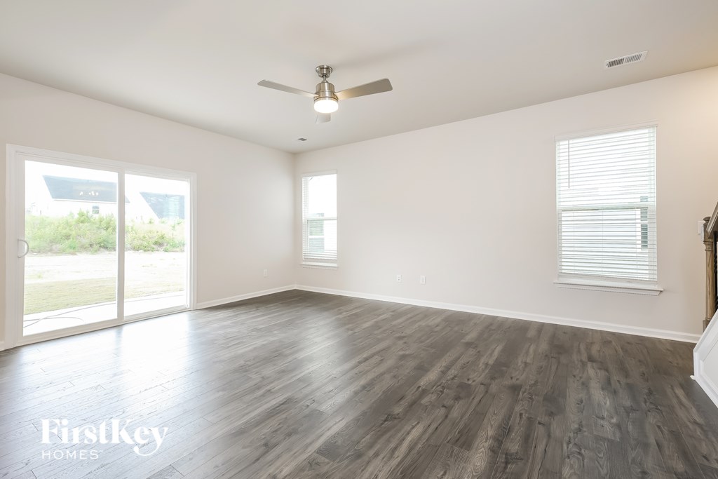 A spacious room with a ceiling fan and sliding glass doors.