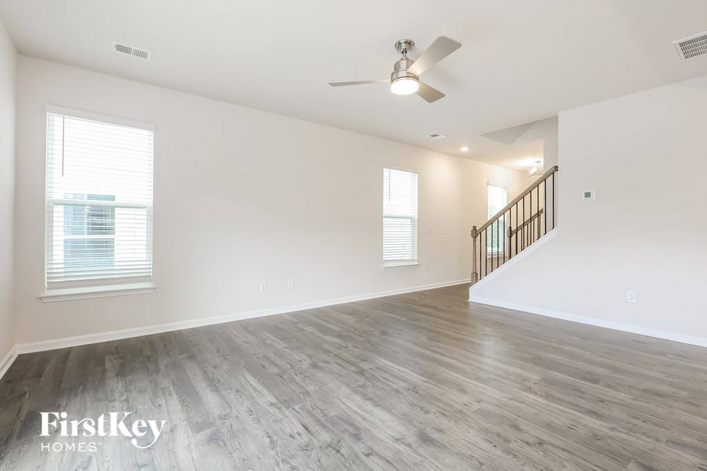 A spacious room with wooden flooring and a staircase.