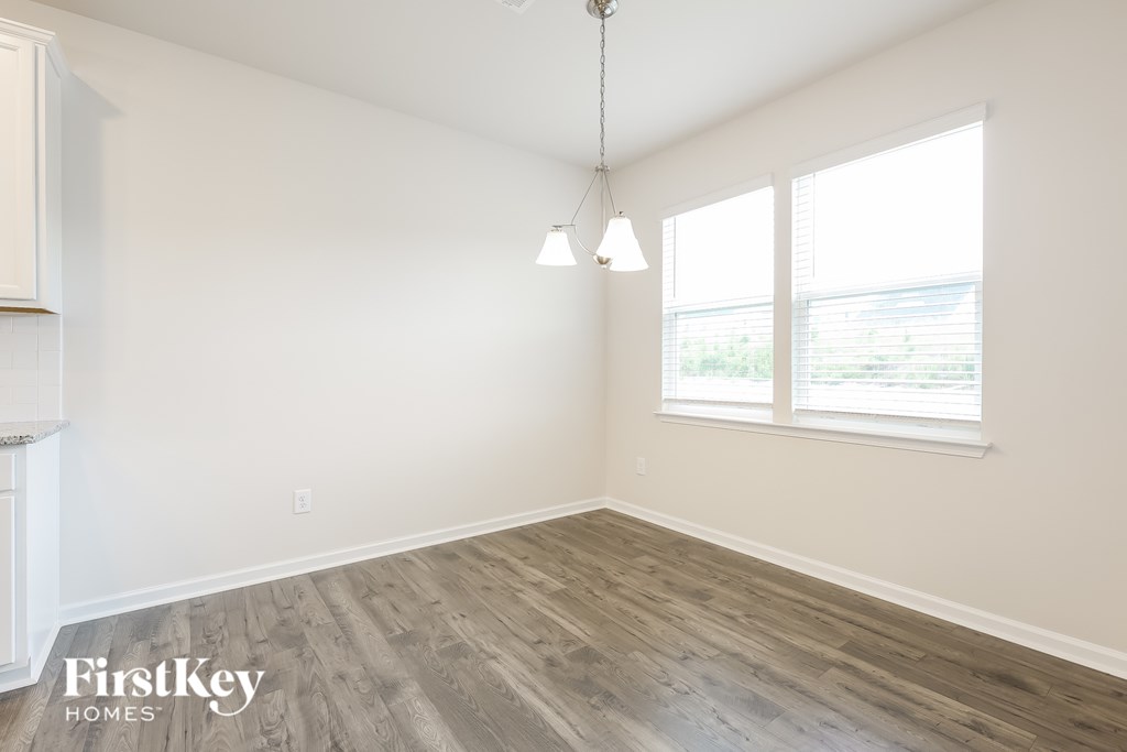 A room with wooden flooring and a window with blinds.