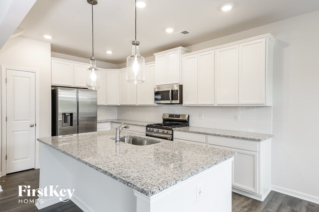 A kitchen with granite countertops and white cabinets.
