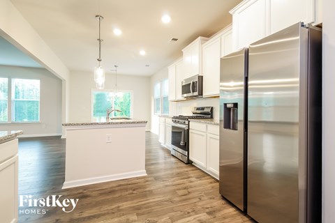 A kitchen with a stainless steel refrigerator and wooden floors.