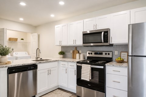 A modern kitchen with white cabinets and stainless steel appliances.