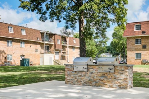 an outdoor barbecue grill in front of a brick building