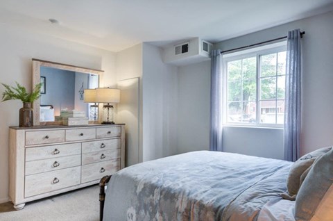 a bedroom with a bed and a dresser and a window