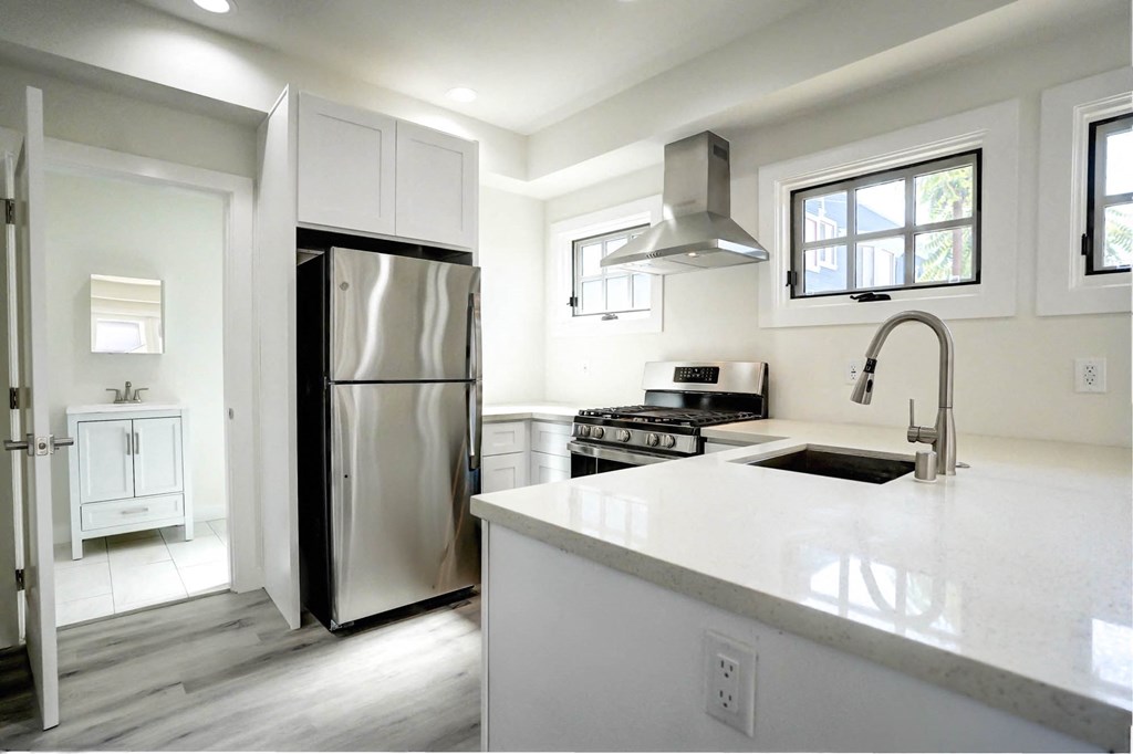 a white kitchen with stainless steel appliances and a large counter top