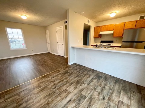 an empty living room and kitchen with wood floors