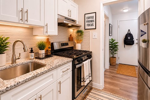 A kitchen with a black stove top oven and a sink with a silver faucet.