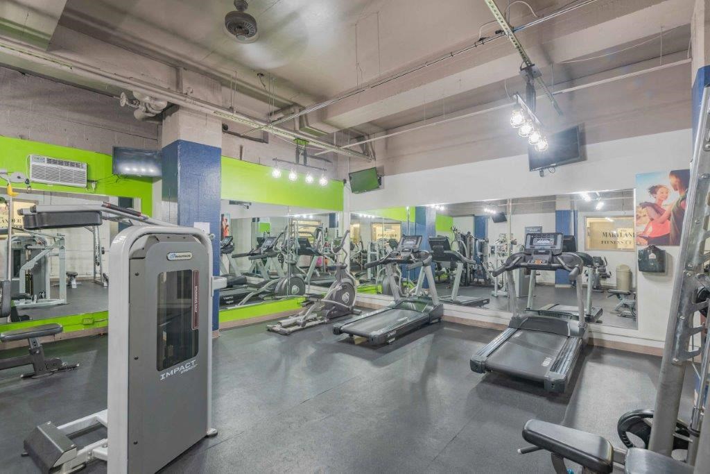 a gym with cardio equipment and weights in a building with green walls