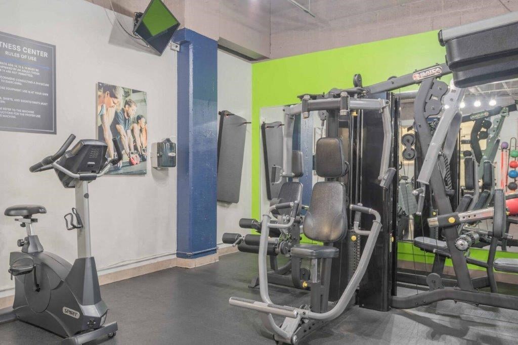 a gym with weights and cardio equipment in a building with green walls