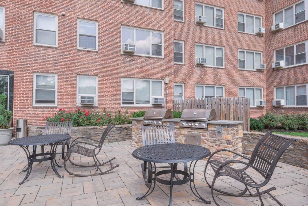 a patio with tables and chairs in front of a brick building