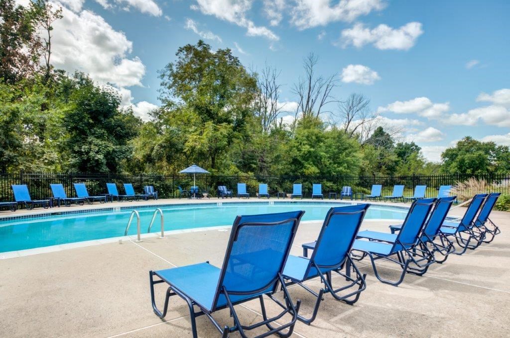a swimming pool with blue lounge chairs and chairs around it
