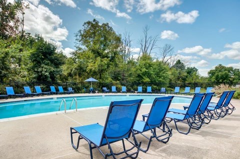 a swimming pool with blue lounge chairs and chairs around it
