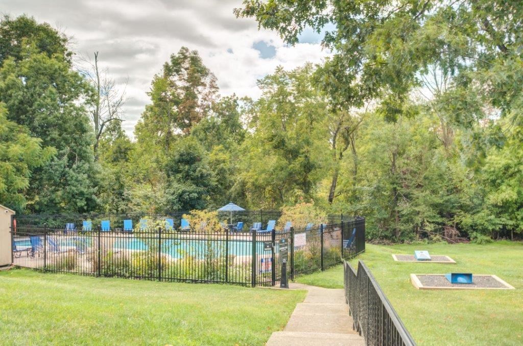 a park with a pool and trees and a fence