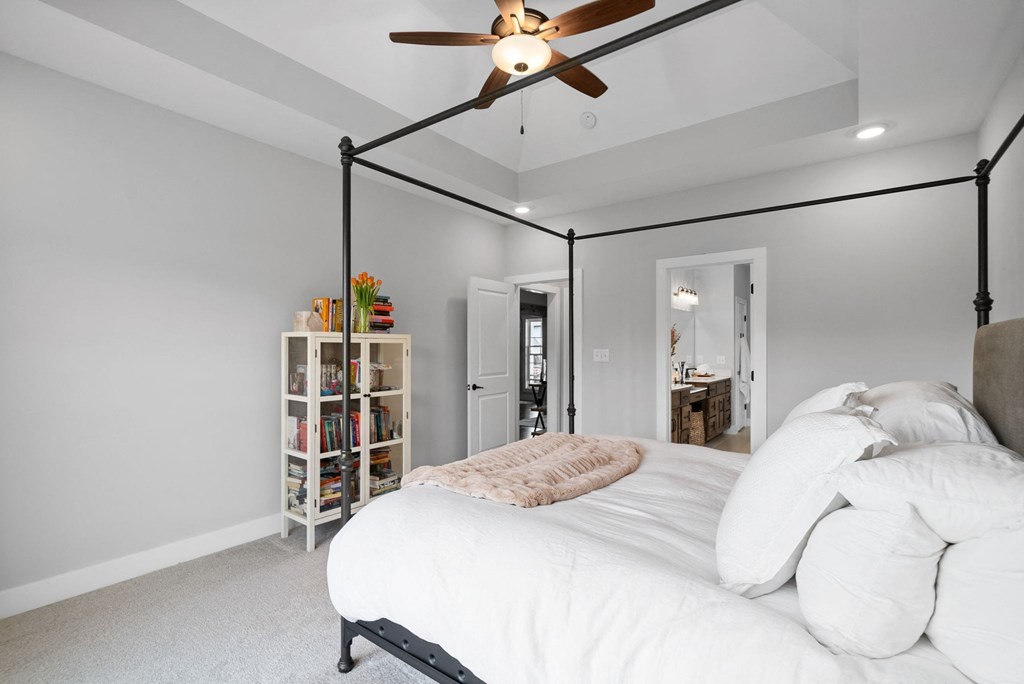 a white bedroom with a large bed and a ceiling fan
