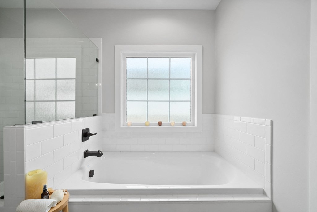 a white bathroom with a tub and a window