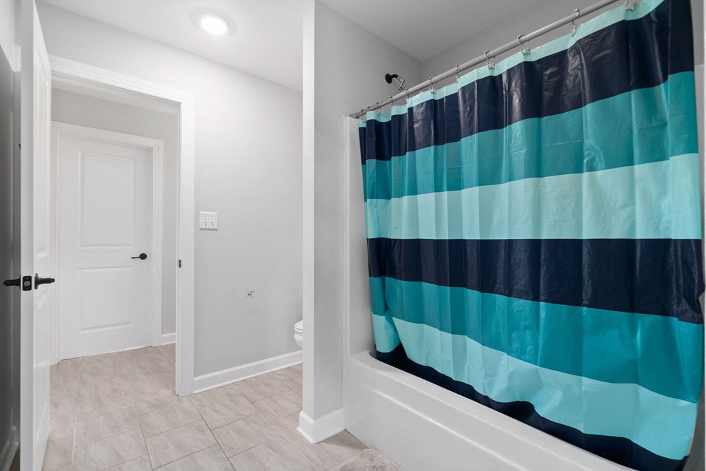 a bathroom with a shower curtain and a white door