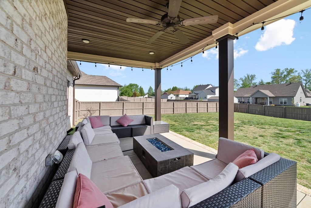 a covered patio with couches and a fire pit