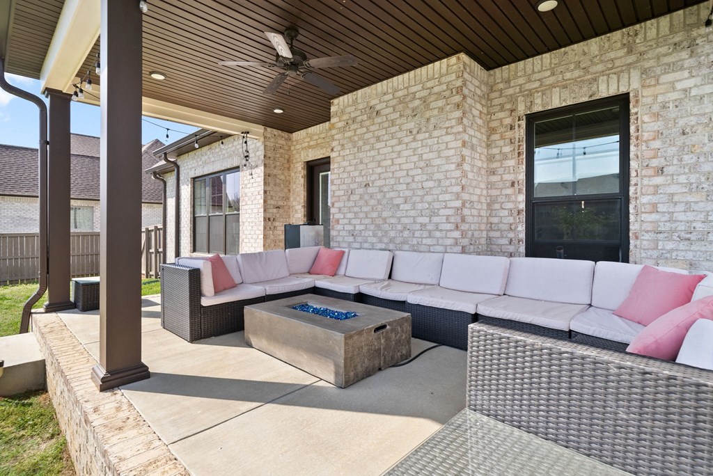 a covered patio with a large white couch and a fire pit