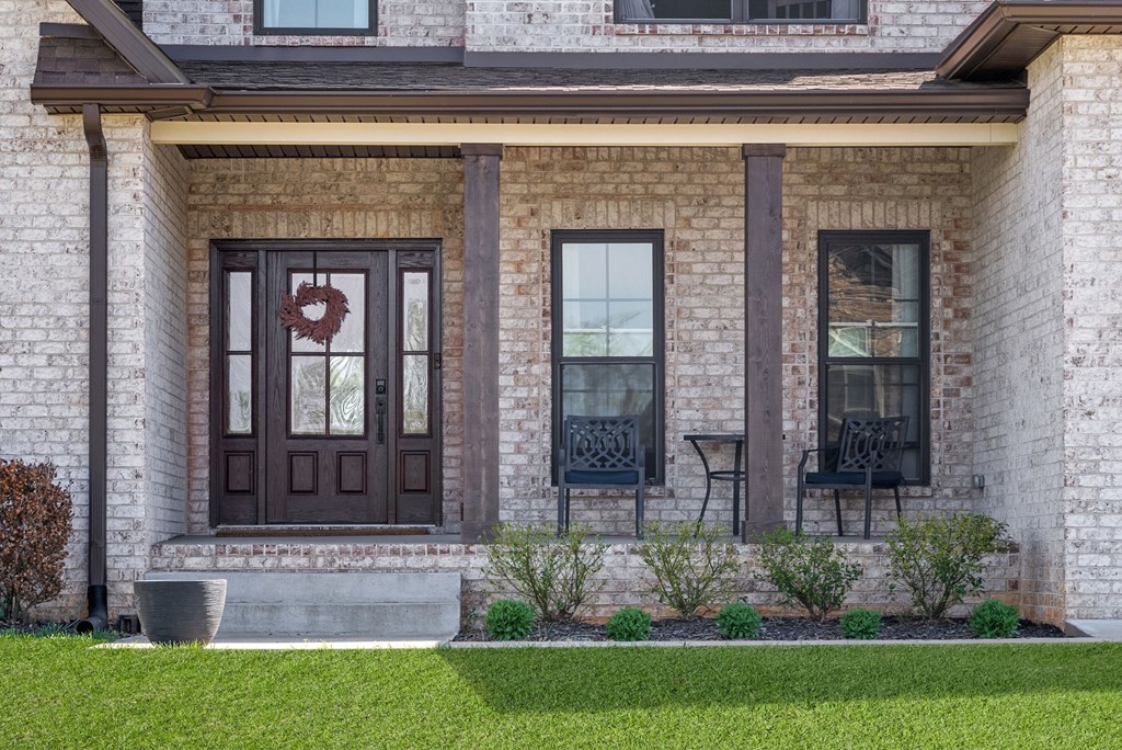 a front porch of a brick house with brown doors and windows