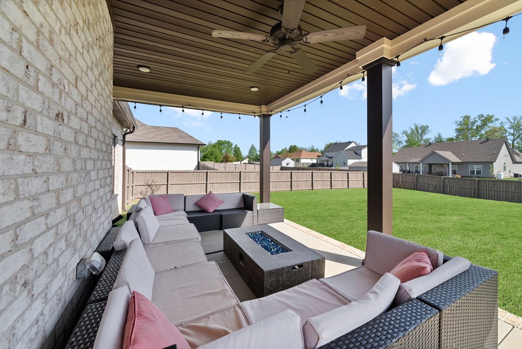 a covered patio with couches and a fire pit
