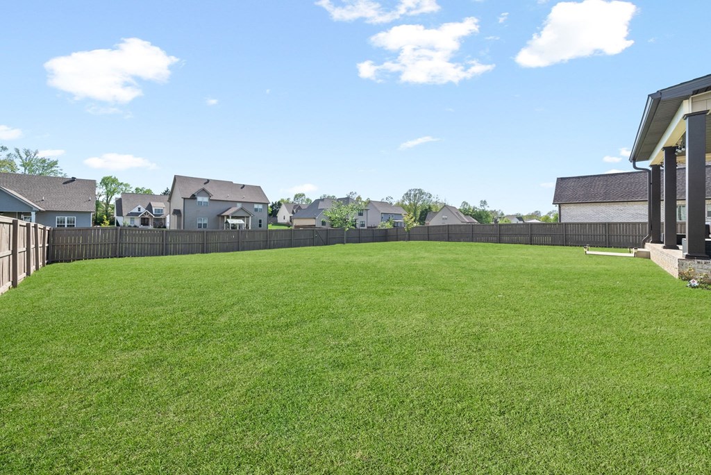 the back yard of a house with a fence and green grass