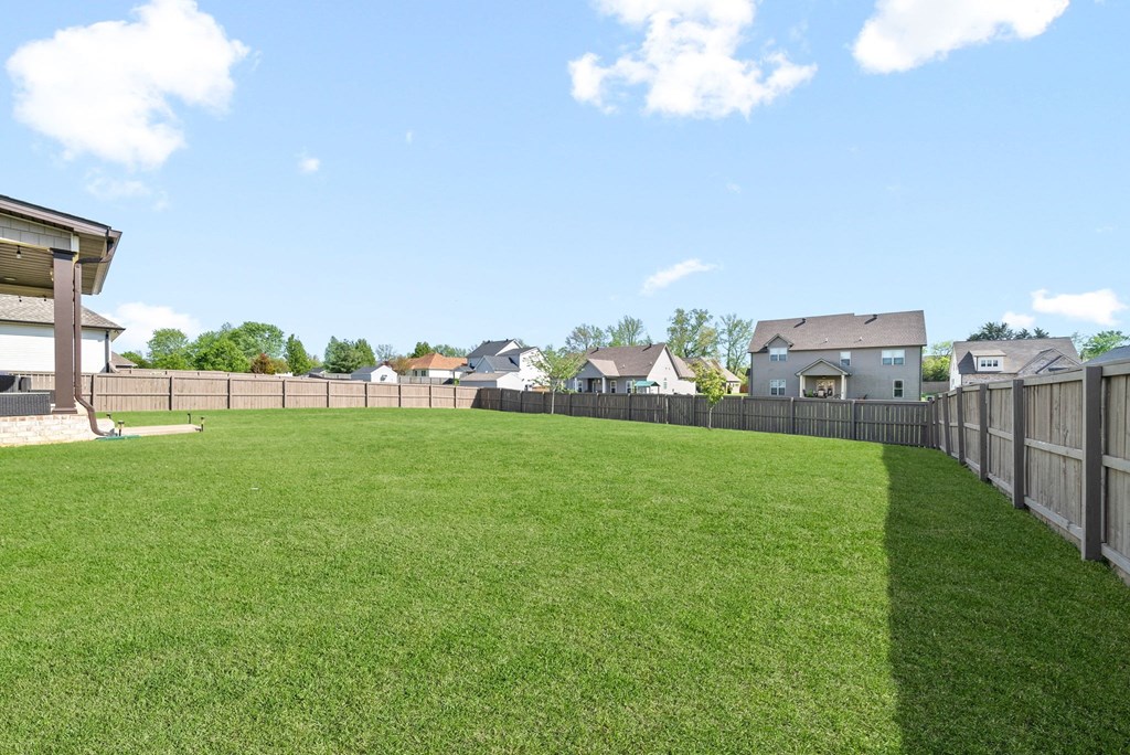 the back yard of a house with a fence and a green lawn
