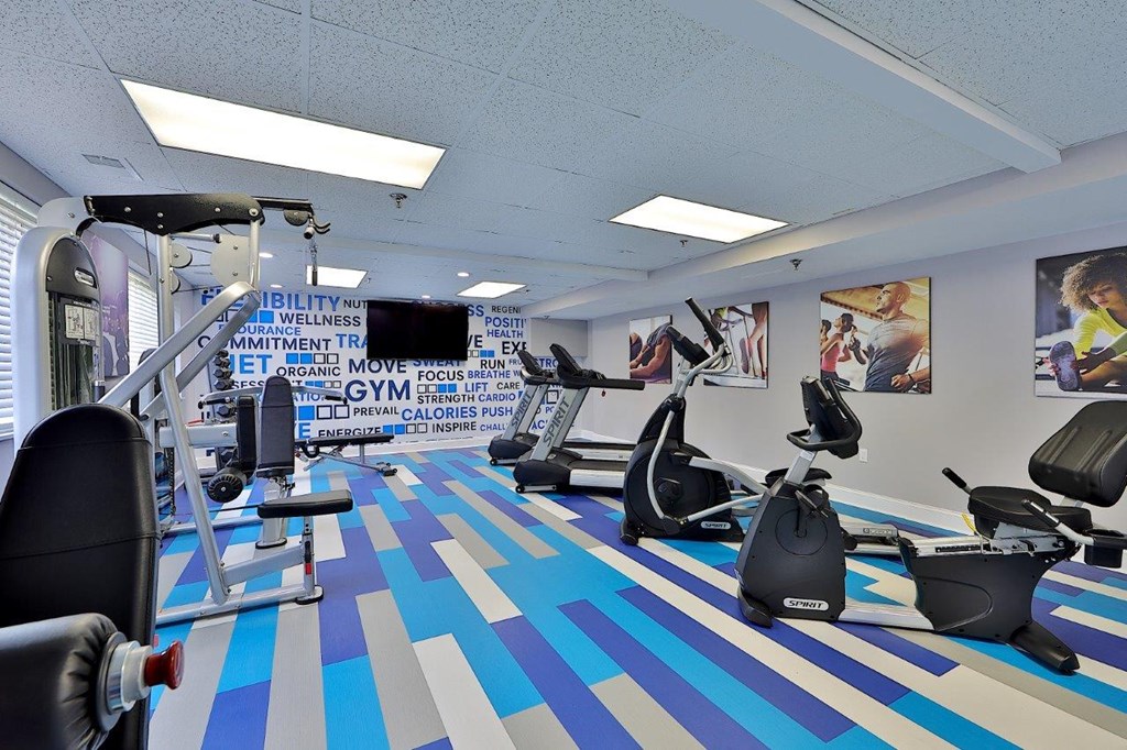 a gym with various exercise machines and a tv