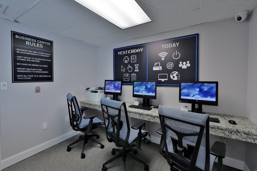 a computer room with four monitors and chairs
