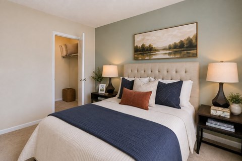 A bedroom with a large bed and a painting on the wall.