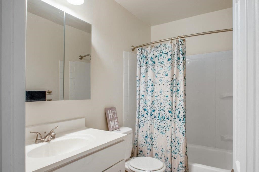 a bathroom with a shower curtain and a sink and a toilet