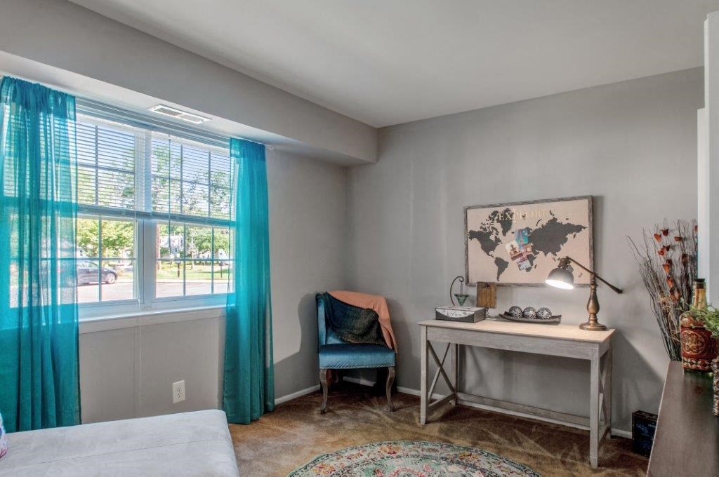 a bedroom with a desk and a window with blue curtains