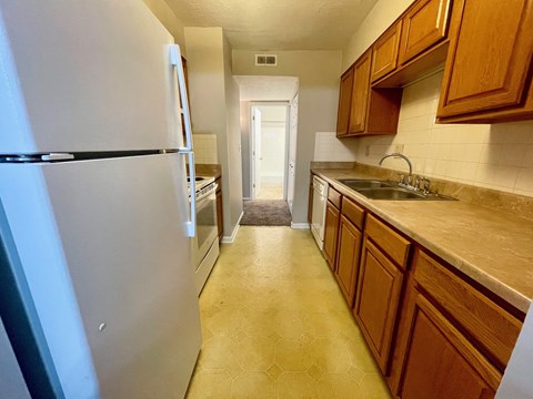 A kitchen with a white fridge and wooden cabinets.