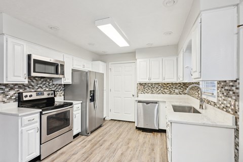 A kitchen with white cabinets and a tile backsplash.