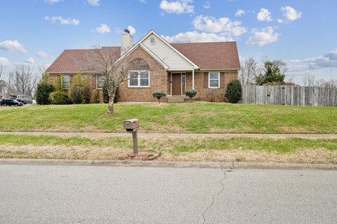 A house with a red brick facade and a mailbox in front.