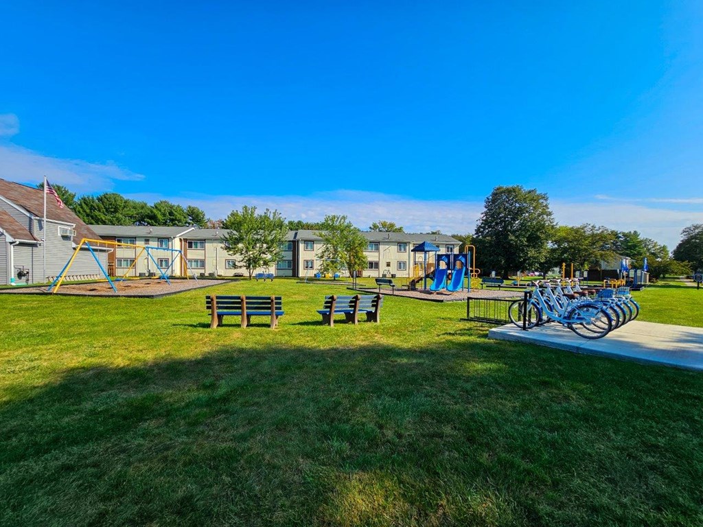 a park with benches and playground equipment in front of houses