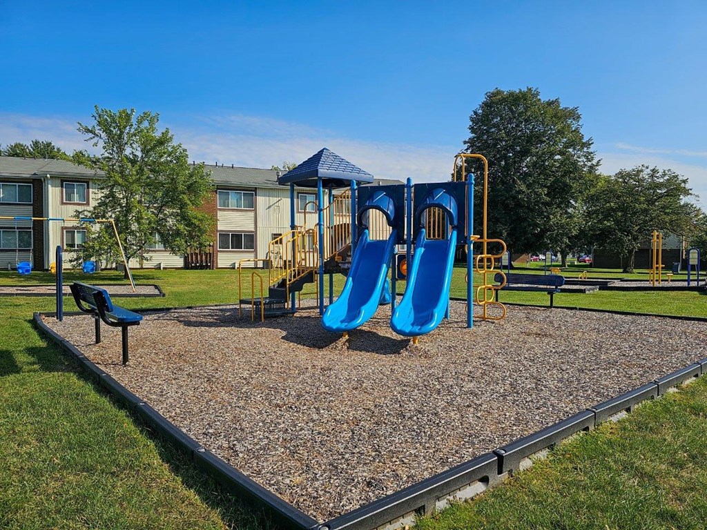 a playground with blue slides and swings in a park
