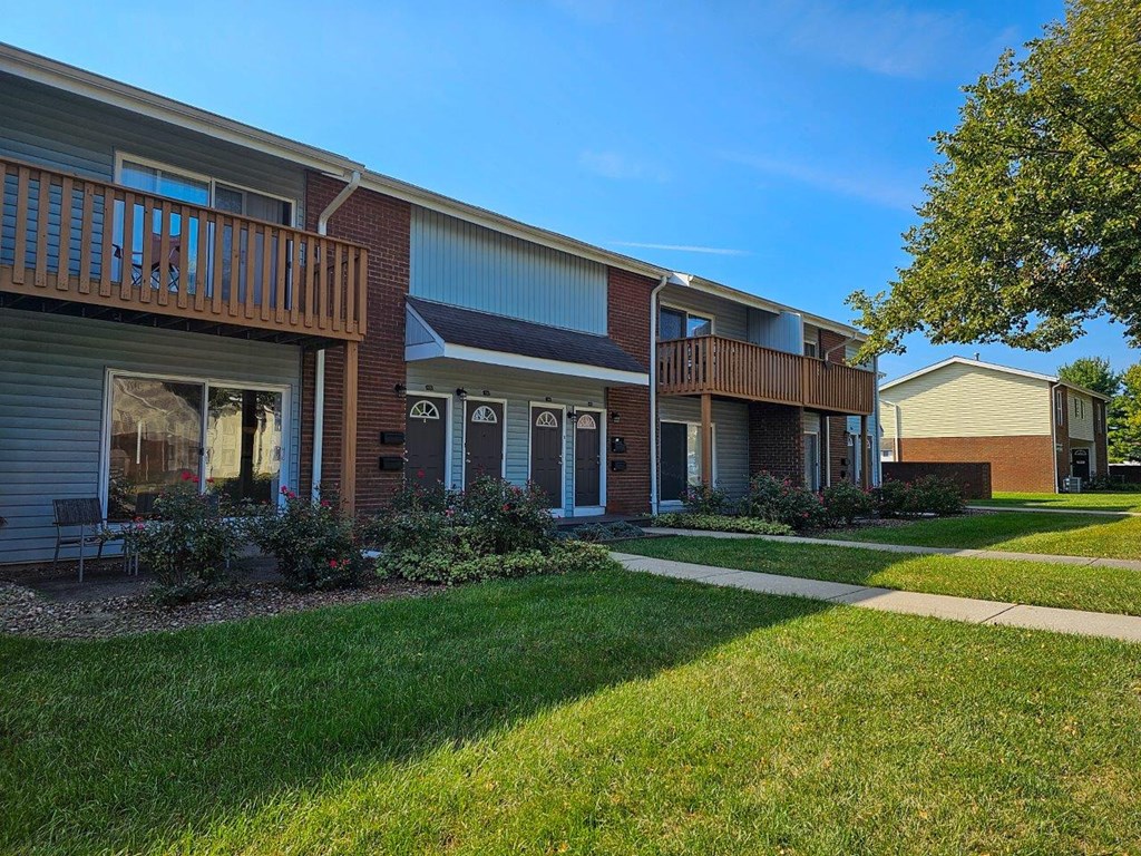 a sidewalk in front of a building with grass