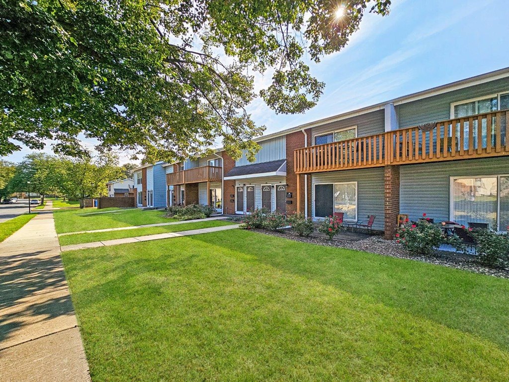 a row of houses with a lawn and a sidewalk