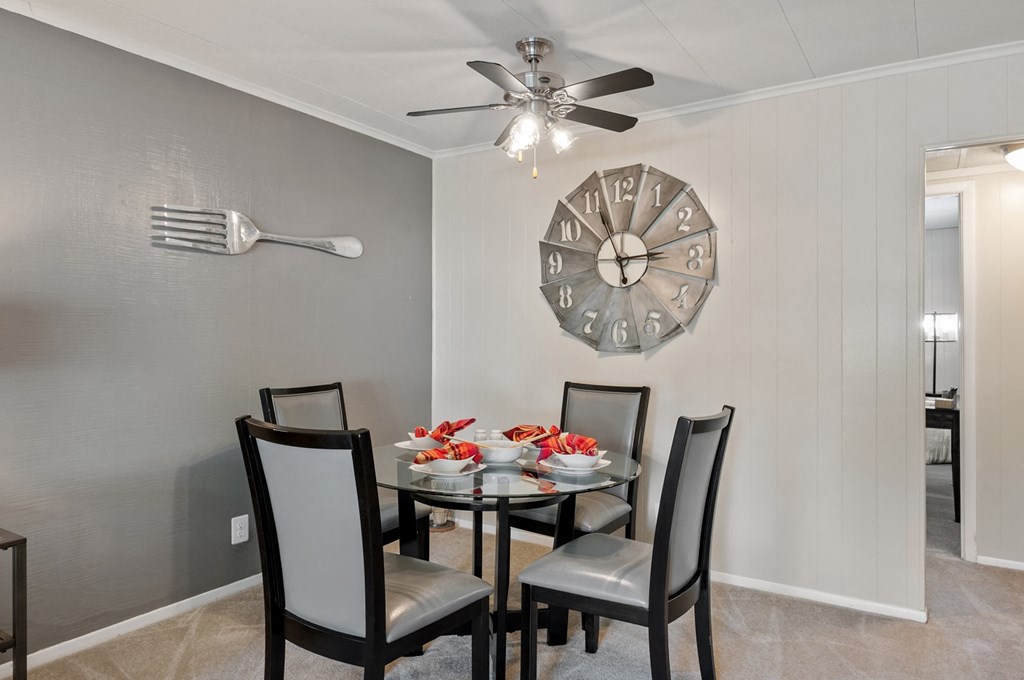a dining room with a table and chairs and a clock on the wall