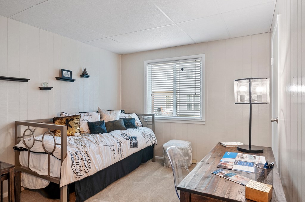 a bedroom with a bed and a desk and a window