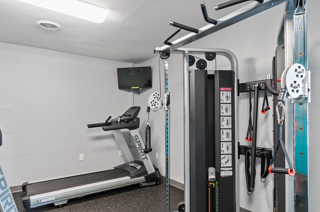 a gym with cardio equipment and weights on the wall