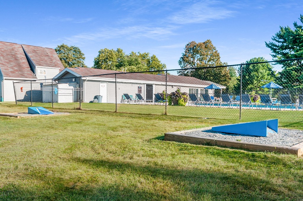 a fenced in backyard with a playground and a pool