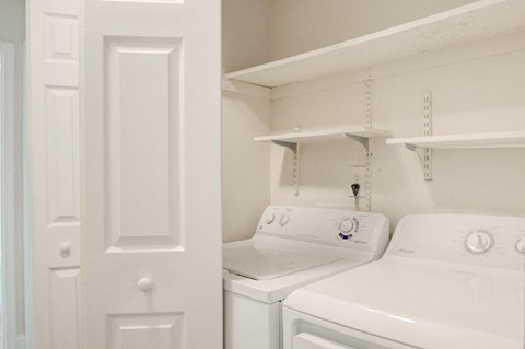a white laundry room with two washes and a dryer