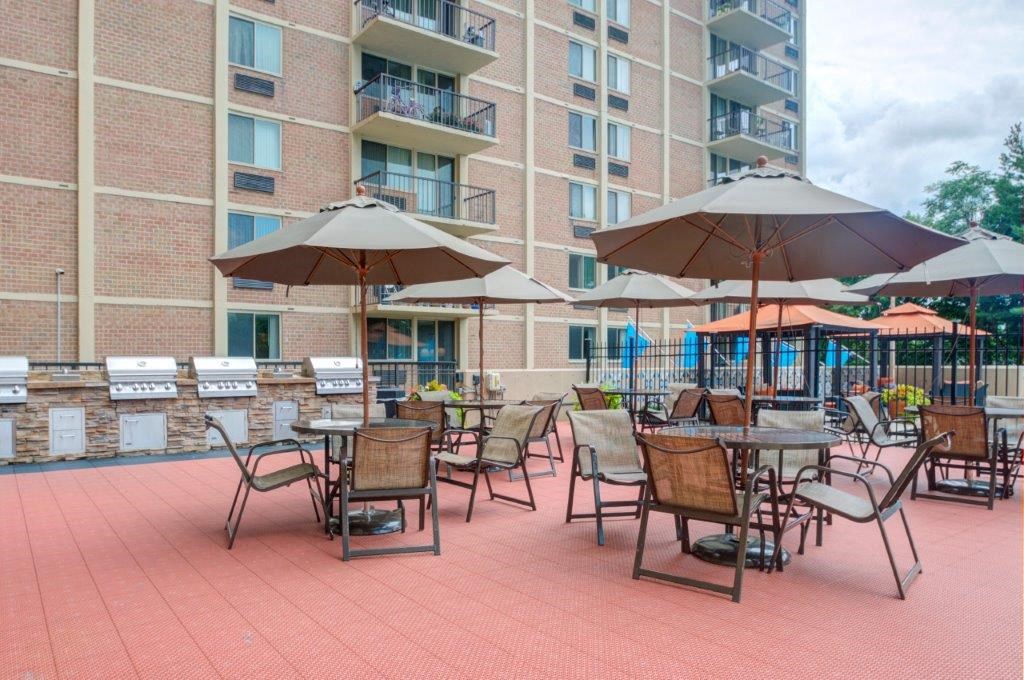 a patio with tables and umbrellas in front of an apartment building