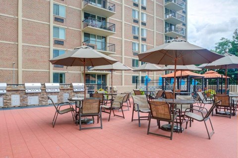a patio with tables and umbrellas in front of an apartment building
