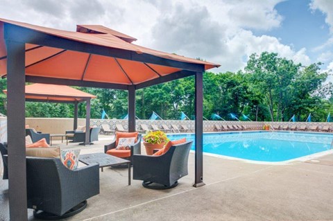 a poolside pavilion with chairs and a pool