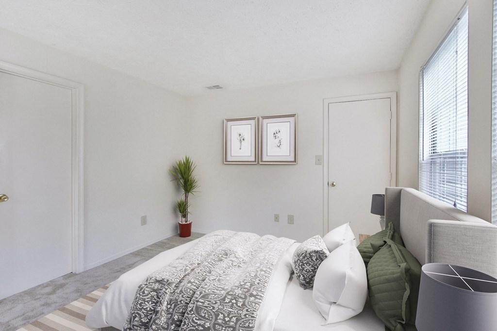 a bedroom with a bed and a chair and a window